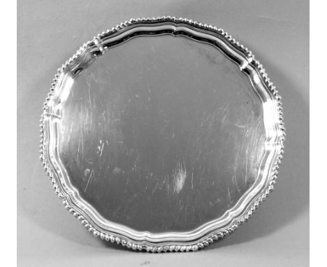 A silver waiter - Sheffield 1981, Roberts &amp; Belk Ltd, of circular ogee form and raised on three scroll feet, diameter 27c