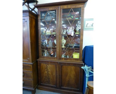 A mid-19th century mahogany glazed cupboard bookcase, the flared pediment over a pair of eleven pane astragal glazed doors, e