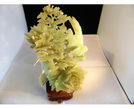 A modern intricately carved jade sculpture of phoenix in a tree upon a wooden stand., 