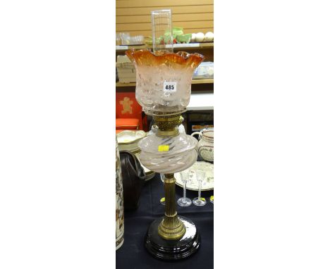 An antique oil lamp with black pottery base, Corinthian brass column stem &amp; pink swirl glass reservoir with tinted glass 