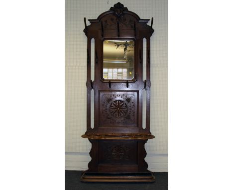 A late 19th century French oak hunting lodge hallstand, the scrolled shield pediment over a canted square mirror within thirt