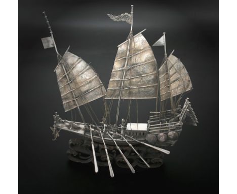 An early 20th century Chinese silver model of a war junk, mounted on pierced hardwood 'wave' base, in it's own hardwood displ