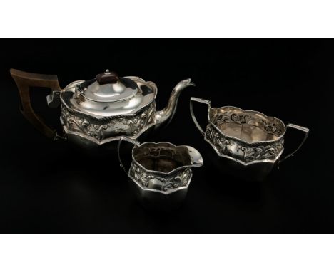 A late Victorian three piece silver tea set, shaped oval with a chased foliate band below ropetwist border, the teapot with f