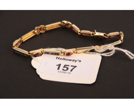 A sapphire and ruby line bracelet,  with bands of calibré cut sapphires interspersed with oval cabochon rubies, marked '585'