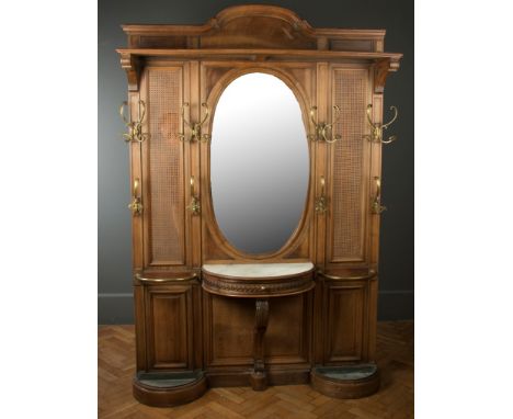 A large late 19th century French chateau walnut and bergere caned hallstand, with central bevelled oval mirror flanked by twe