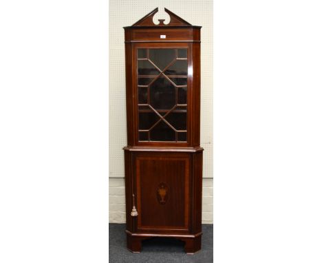 An Edwardian mahogany corner vitrine, the broken architectural pediment over a strung astragal glazed door enclosing two shel