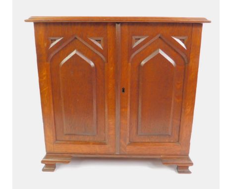 A Victorian Gothic oak stationery cabinet, with a pair of carved arched panel doors enclosing a fitted interior, of four rece