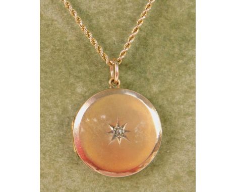 A diamond set circular double photo locket, rose metal, stamped 9ct front and back, on a yellow metal rope twist chain, stamp