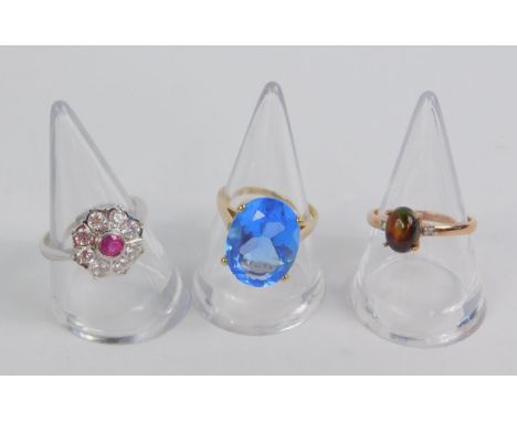 A 9ct white gold ruby and cubic zirconia flower head ring, size O, 9ct gold and blue stone ring, high claw set, size M, and a