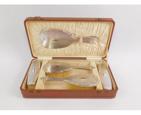 A George V silver backed toilet set, with engine turned and engraved floral decoration, cased, comprising hand mirror, pair o