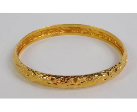 A floral engraved bangle, set in high grade yellow metal, 21.9g. 