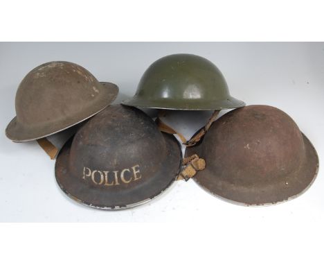 A WW II British Home Front Police Brodie helmet, having a black leather liner and canvas chin strap, together with three othe