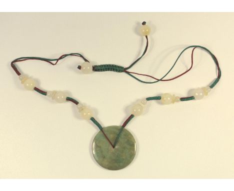 ORIENTAL HARDSTONE BEAD AND SILK NECKLACE WITH A GREEN JADE DISC PENDANT (DIA. 5 CM) 