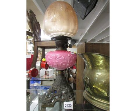 A Victorian oil lamp with pink glass font and original etched shade.
