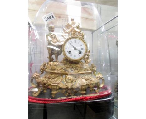A French gilded mantel clock under glass dome.