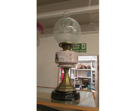 A late Victorian oil lamp with painted glass font, brass and ceramic base and etched shade, in good condition.