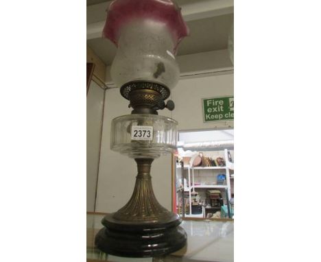 A late Victorian oil lamp with glass font and original shade.