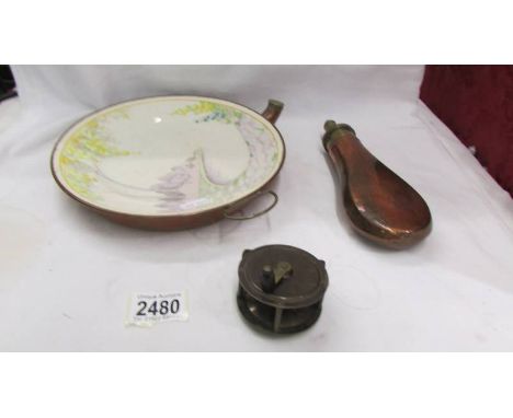 A copper bases warming plate, a copper powder flask and an old fishing reel.