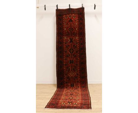 A Baluchi runner,of recent manufacture, with repeating medallions to a red field,401 x 92cmCondition ReportOne end discoloure