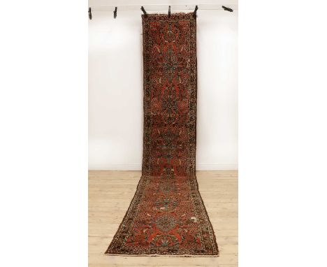 A hand knotted Persian runner,20th century, the red fields with repeating foliate decoration in a triple border,516 x 81cmCon