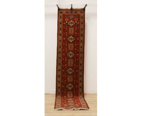 A Caucasian runner,of recent manufacture, with repeating medallions to a red field,338 x 75cms