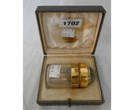 A 1933 fitted leather presentation case containing an unmarked yellow metal flip-top pill bottle, set with large chrysoberyl 