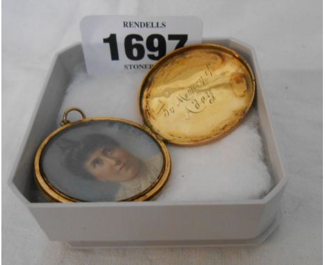 An antique engine turned yellow metal circular mourning locket with internal portrait miniature and memorial text
