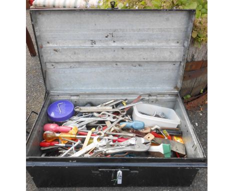 A black japanned tin box containing a quantity of assorted tools, including spanners, screwdrivers etc.