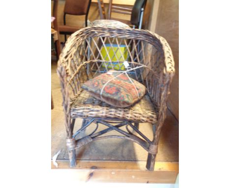 A vintage child's wicker tub chair with cushion