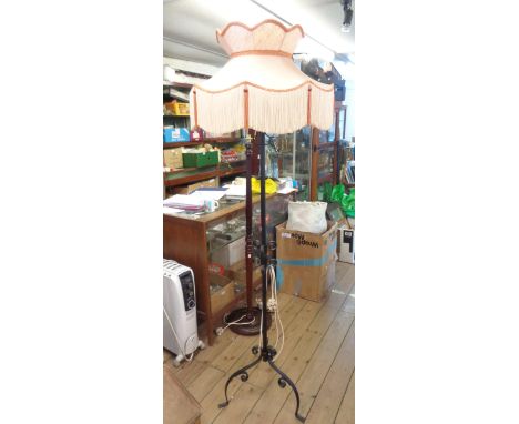 A wrought iron standard lamp with shade