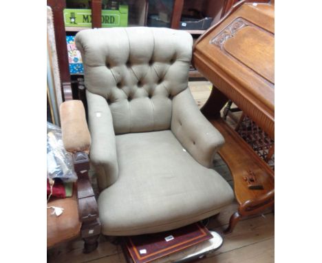 A late Victorian low armchair with button back green cotton upholstery, set on turned front legs and casters