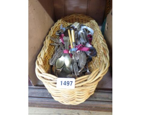 A wicker tray containing a quantity of assorted silver plated and other cutlery