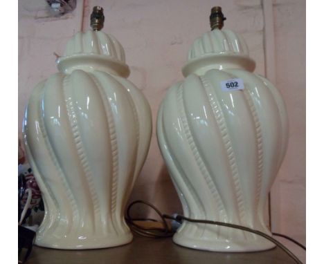 A pair of large decorative ceramic urn form table lamps in an ivory coloured glaze