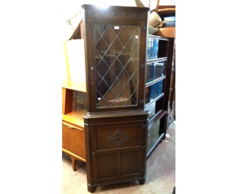 A reproduction oak corner cabinet with leaded glazed top and cupboard under, set on bracket feet