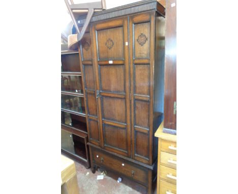 An 88cm early 20th Century oak and mixed wood single wardrobe with panelled door and drawer under, set on bracketed legs