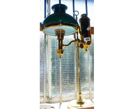 An old polished brass student's table lamp with cylinder reservoir and green opaque glass shade