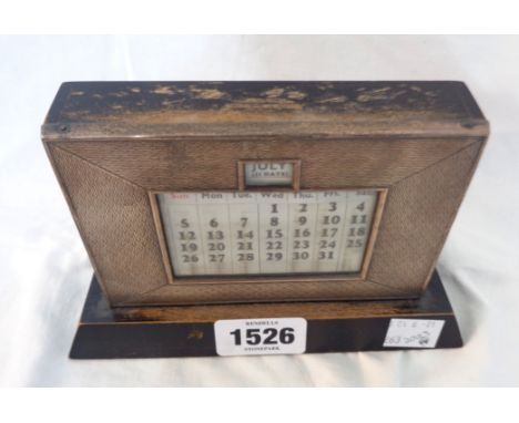 A vintage silver fronted desk calendar with engine turned decoration and painted wood base