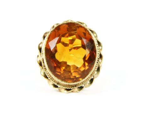 A gold single stone oval cut mixed citrine ring, rub set to a twisted rope border, split shoulders and a plain polished shank