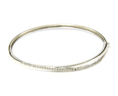 A 9ct white gold diamond set hinge bangle, (one stone deficient), 7.78g
