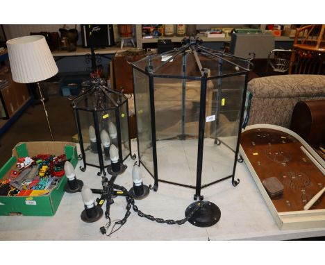 A large wrought iron and glass light fitting with another smaller similar