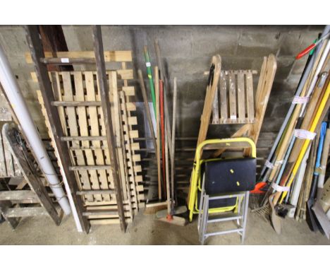 A quantity of long handled tools to include brooms, rakes etc