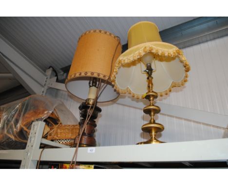 A brass table lamp and shade and a wooden candlestick style example 
