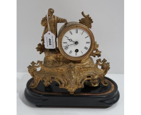 A gilded metal mantle clock, modelled as a standing scholar, beside a drum head cock, with key and pendulum, on wooden stand,