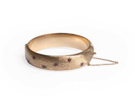 A 9 Carat Gold Ruby Hinged Bangle, the textured upper half decorated with round cut rubies in yellow star settings, to a plai