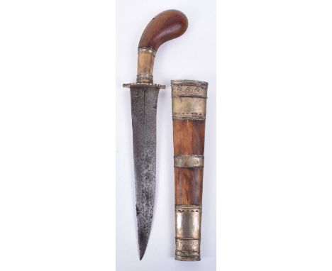 A 20th Century Malaysian Kris dagger, wooden shaped handle and white metal mounts, the wooden scabbard with engraved metal mo