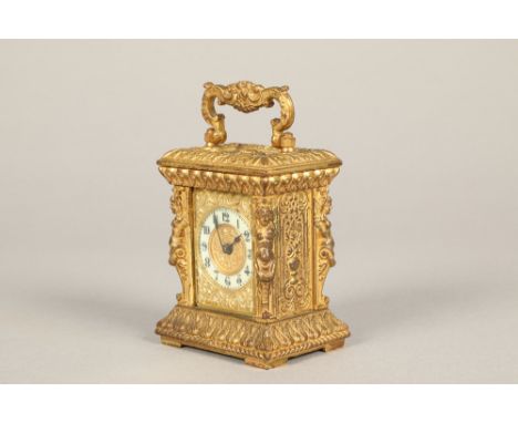 Gilt brass carriage clock, with a cut out dial and enamel chapter ring, black numerals, swing handle with key. 12cm high incl