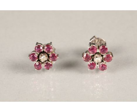 Boxed pair of diamond and ruby earrings, each earring set with a single central diamond surrounded by six rubies. Rubies meas