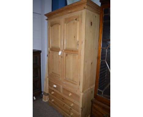 A modern Victorian style pine wardrobe, with flared cornice above two arched fielded panel doors enclosing hanging space and 