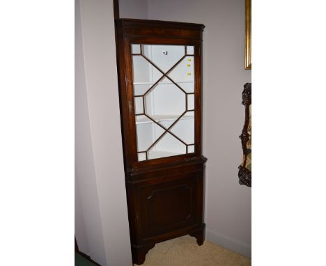 A mahogany corner display cabinet with flared cornice and a single glazed panel door enclosing painted interior with shelves,