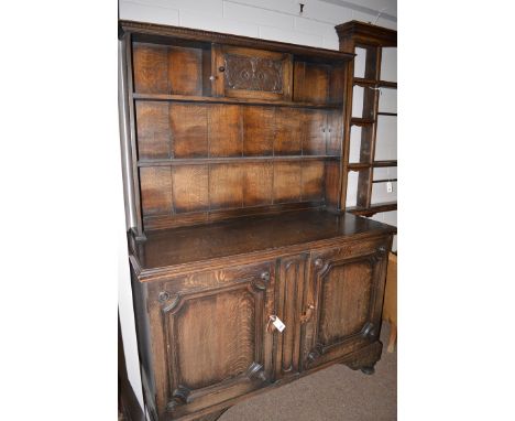 A mid 20th Century oak dresser with two tier panelled delft rack fitted to cupboard with carved panel door above a base with 